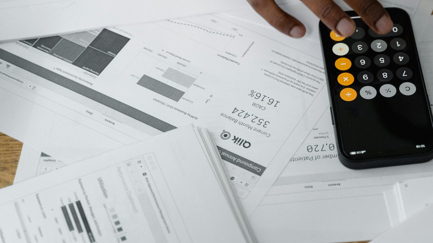 Main sur une calculatrice posée sur des documents financiers, illustrant l'argent à réclamer dans ses impôts en Suisse